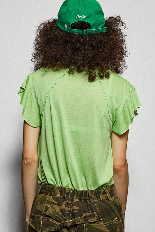 Person wearing a green t-shirt and cap with camouflage pants on a plain background