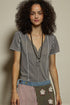 Woman wearing a gray striped shirt with a patterned skirt against a beige background