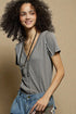 Woman wearing a gray top and blue jeans against a beige background