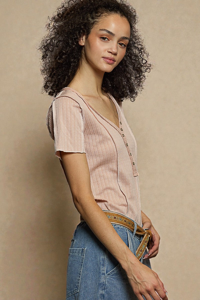 Woman wearing a light pink blouse and blue jeans against a beige background