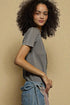 Woman wearing a gray ribbed top and blue jeans against a beige background