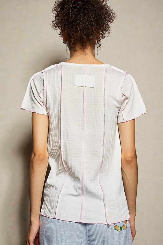 Person wearing a light-colored top with a subtle pattern on a plain background