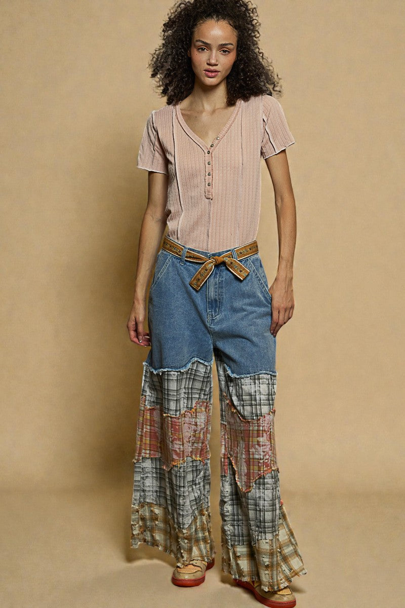 Woman wearing a pink top and plaid pants against a beige background