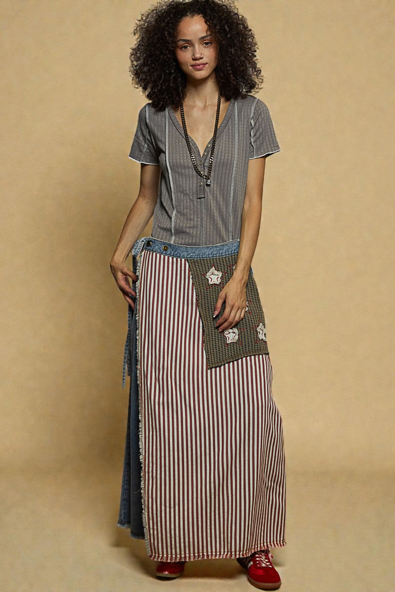 Woman wearing a gray top and striped skirt against a beige background