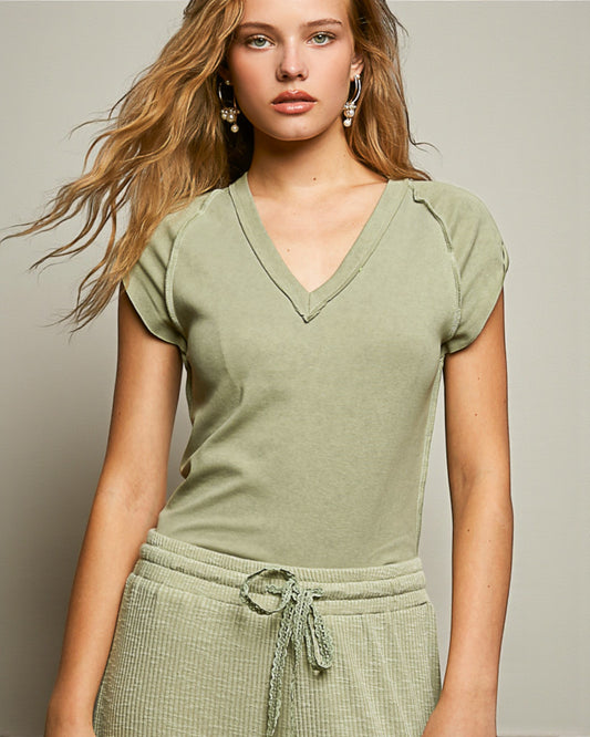 Woman wearing a green V-neck top and green pants against a neutral background