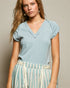 Woman wearing a light blue top and striped pants against a neutral background