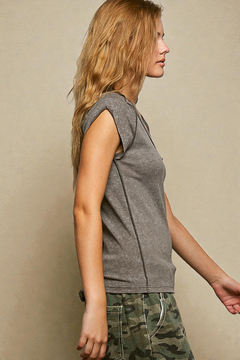 Woman wearing a gray sleeveless top and camouflage pants against a beige background