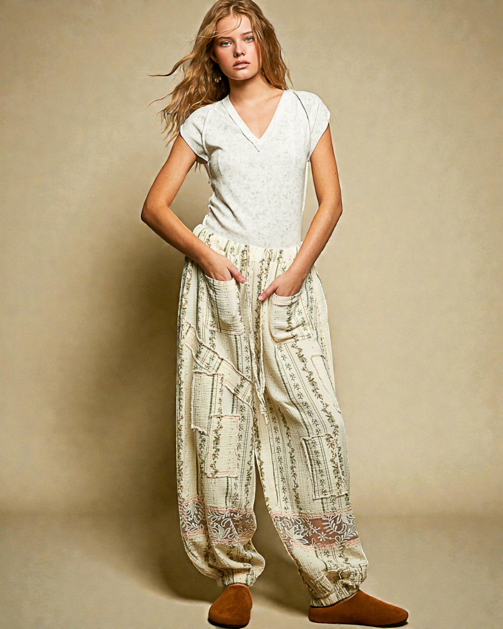 Woman wearing a white top and patterned pants against a beige background