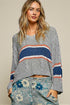 Woman wearing a gray sweater with colorful stripes on a beige background