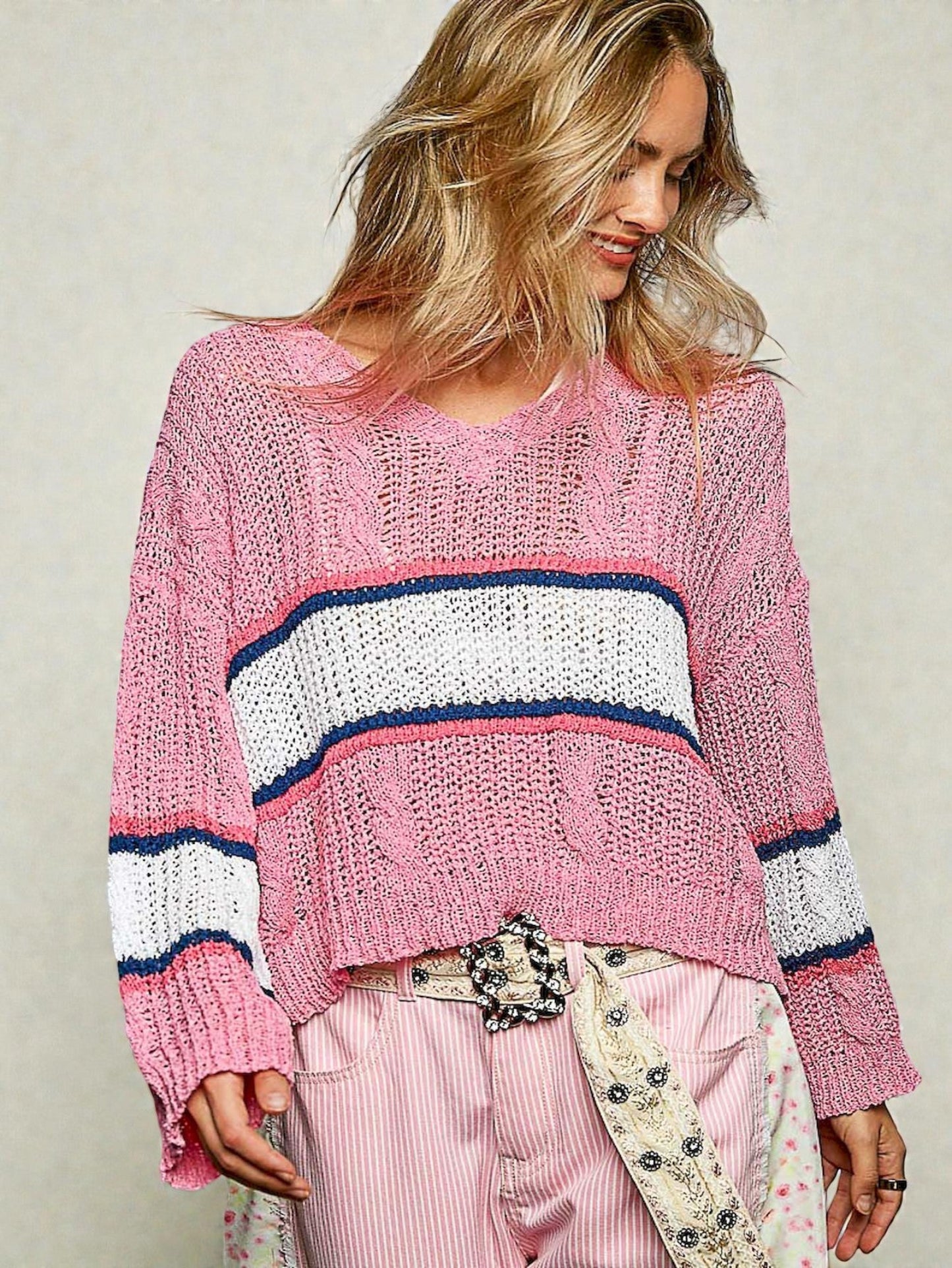 Woman wearing a pink sweater with a striped pattern on a plain background