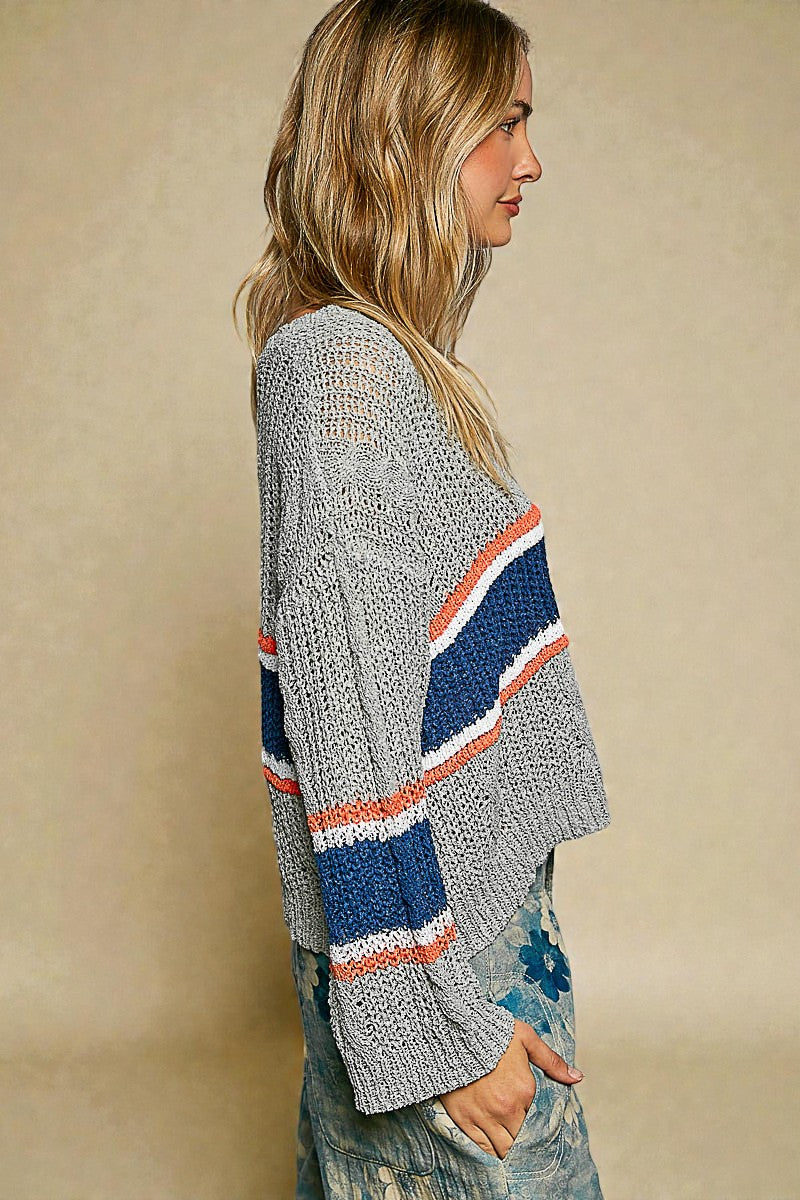 Woman wearing a gray cardigan with colorful stripes on a beige background