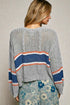 Woman wearing a gray knit sweater with colorful stripes on a neutral background