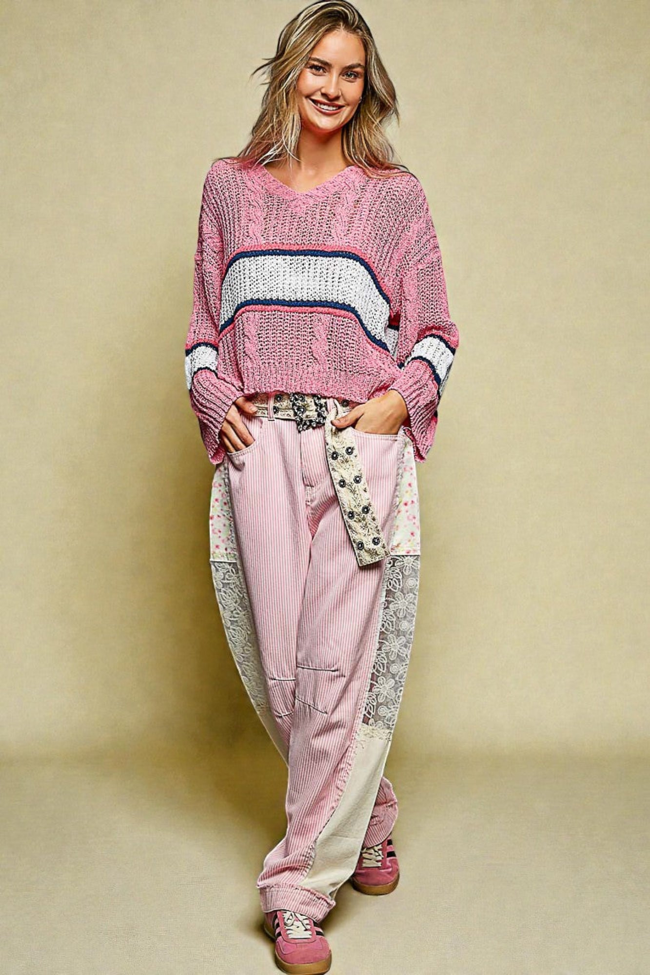 Woman wearing a pink sweater and pants with a beige background