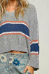 Gray sweater with colorful stripes worn by a person, with a neutral background