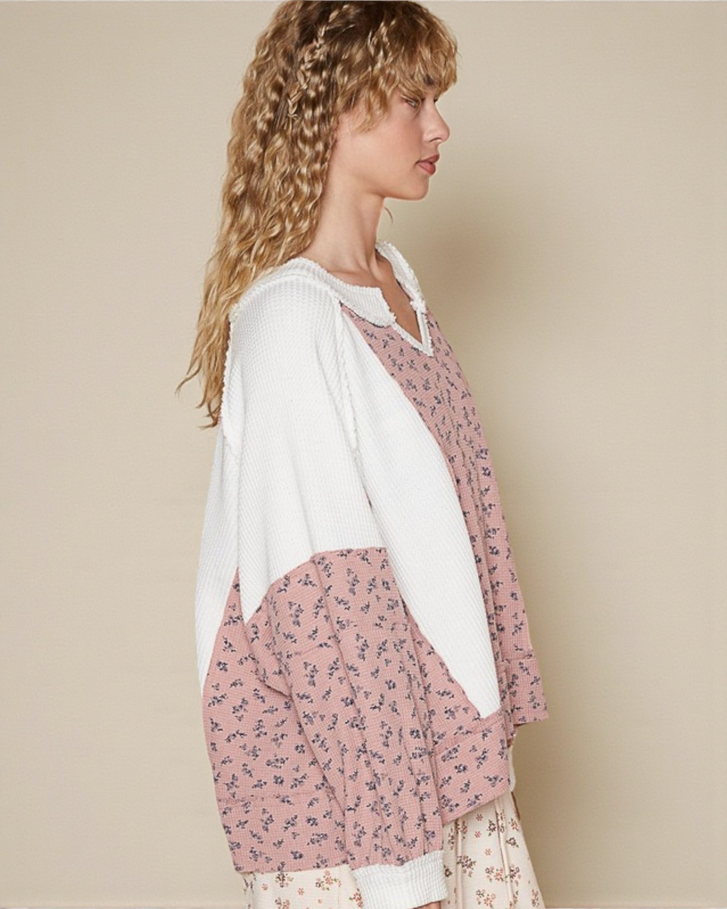 Woman wearing a pink floral dress with a white cardigan against a beige background