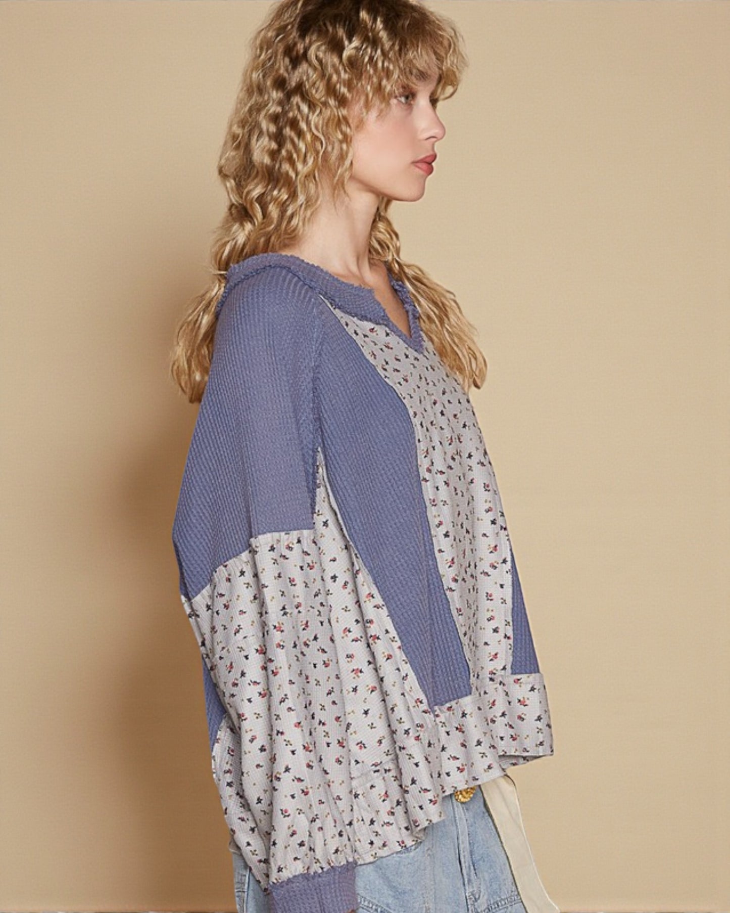 Woman wearing a blue and floral-patterned cardigan against a beige background