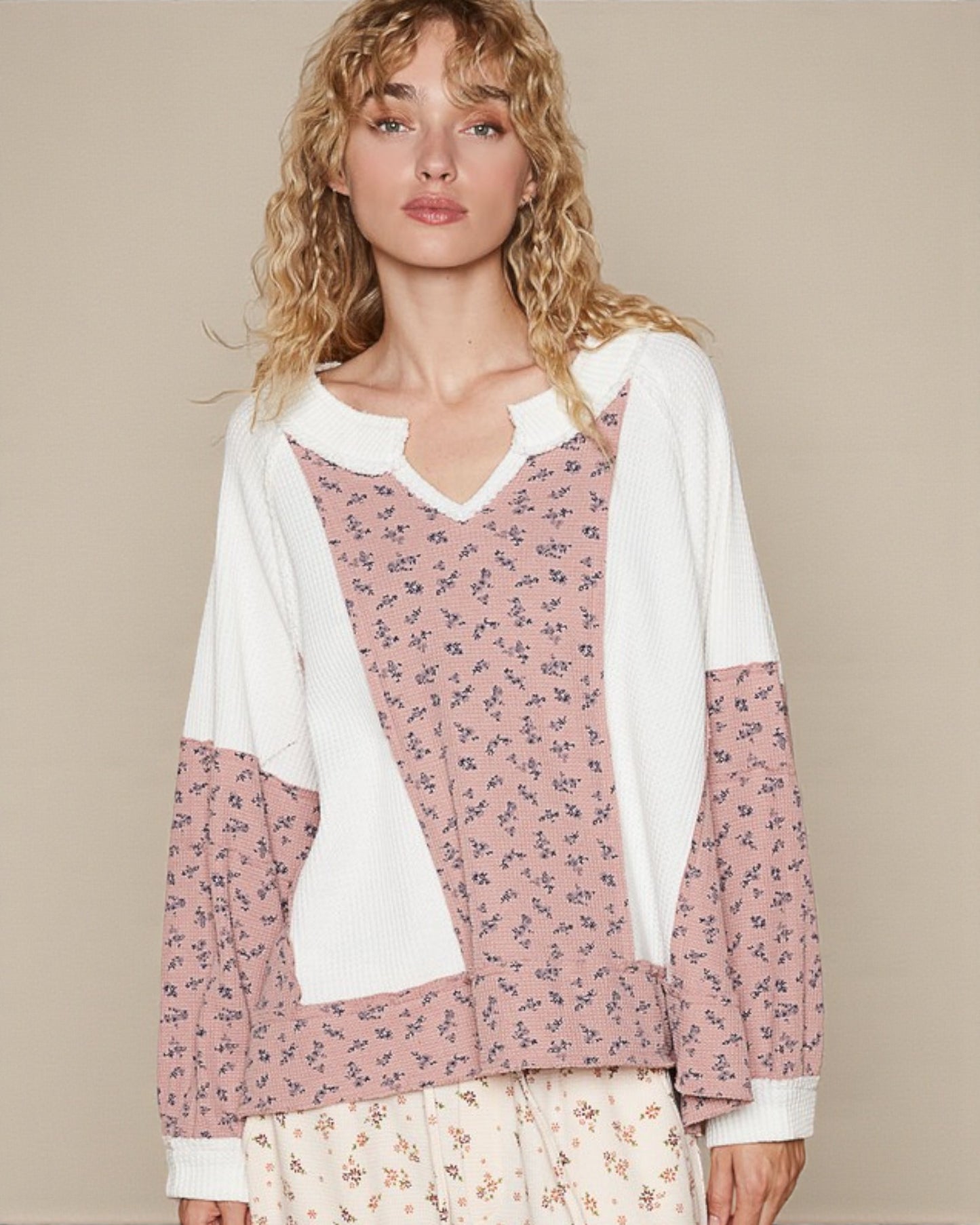 Woman wearing a pink floral top with white accents on a beige background