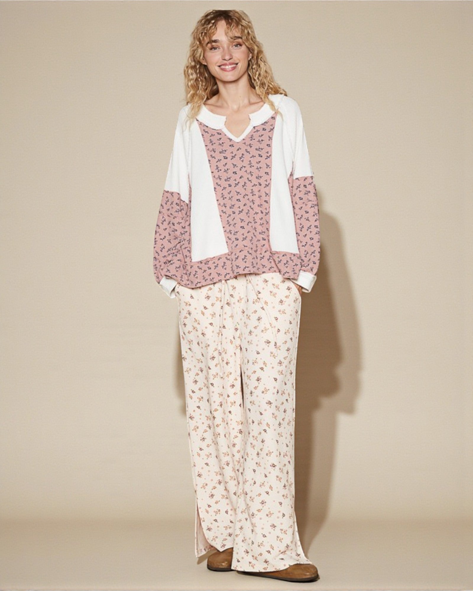 Woman wearing a floral top and pants with a beige background