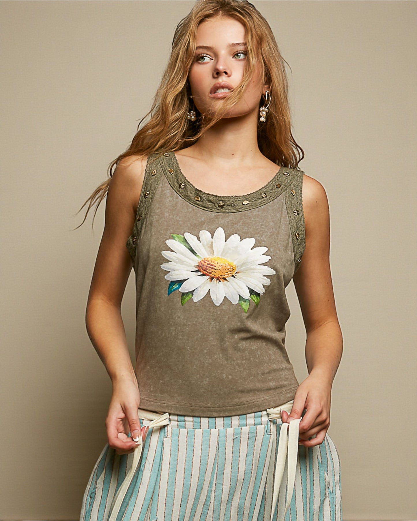 Woman wearing a sleeveless top with a floral design against a beige background