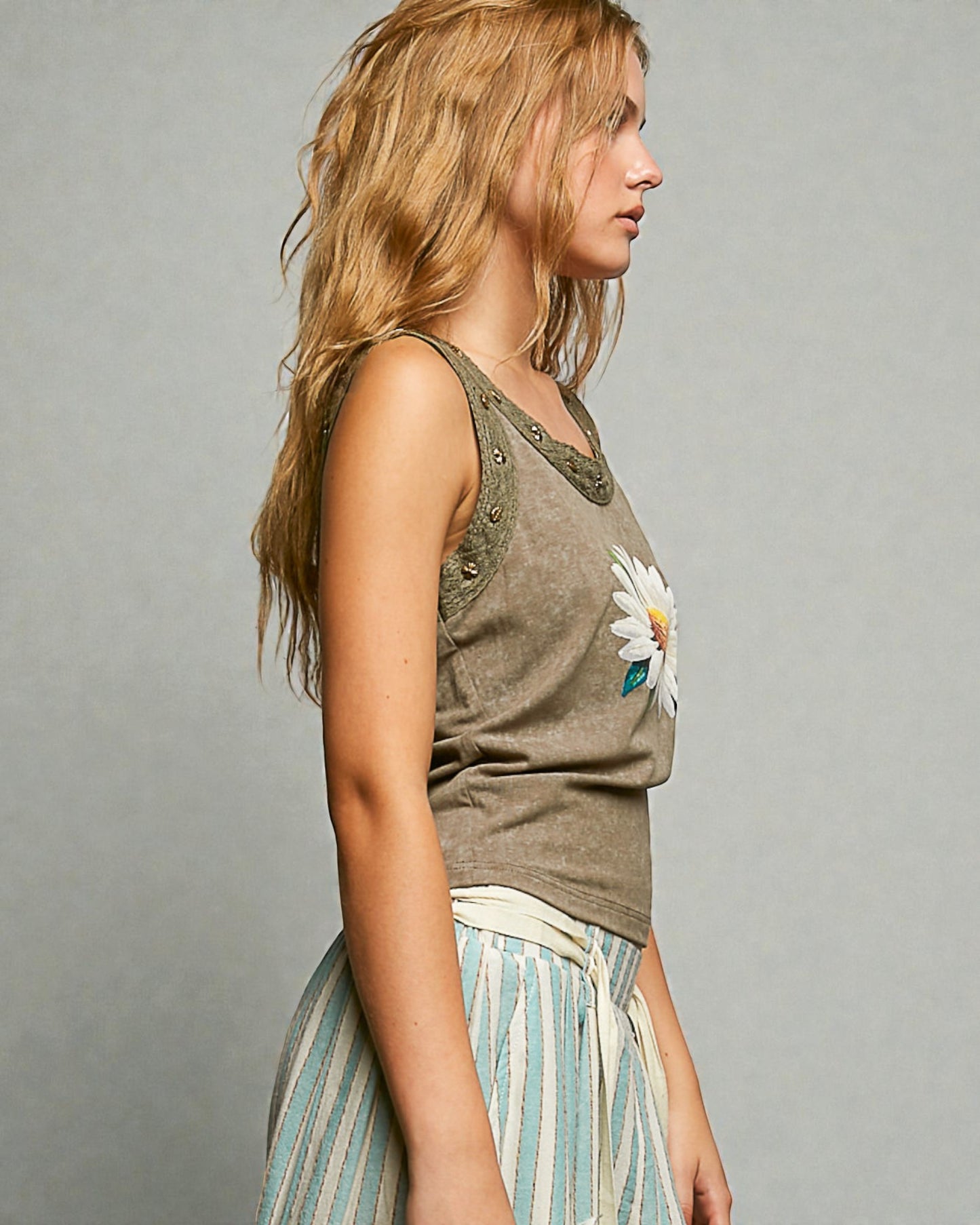 Woman wearing a sleeveless top with a floral design on a gray background