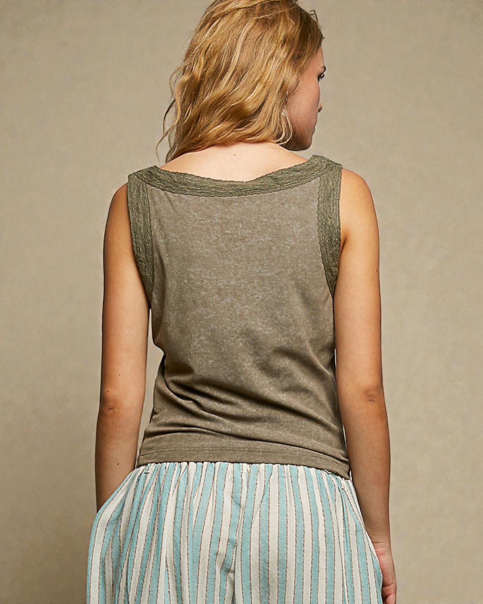 Woman wearing a green sleeveless top with a beige background