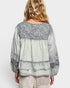 Woman wearing a light gray blouse with lace details on a white background