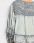 Light gray blouse with lace details on a white background