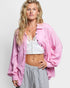 Woman wearing a pink shirt over a white top and striped pants on a light background