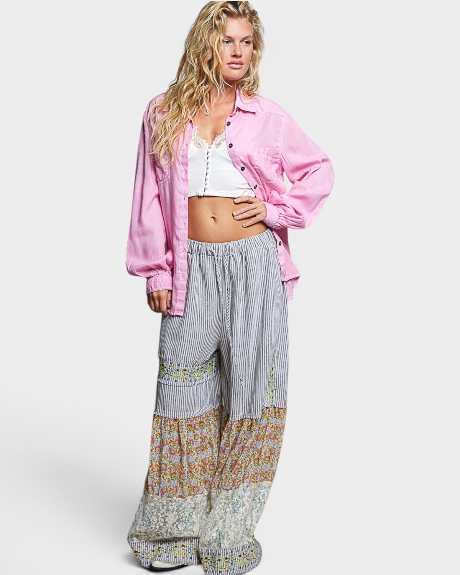 Woman wearing a pink shirt and patterned pants on a white background