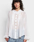 Woman wearing a white blouse with ruffled details on a plain background