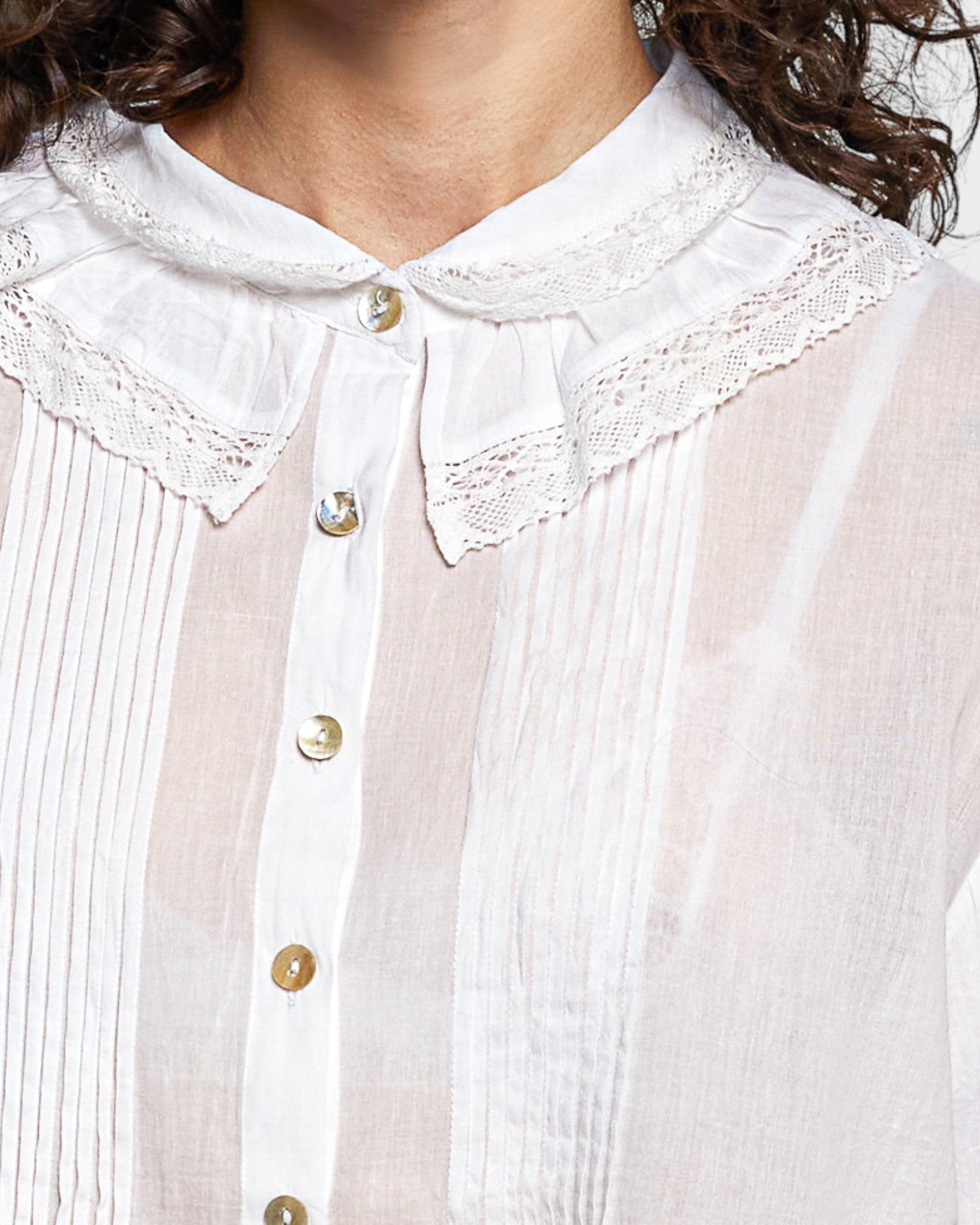 Close-up of a white blouse with lace collar and buttons.