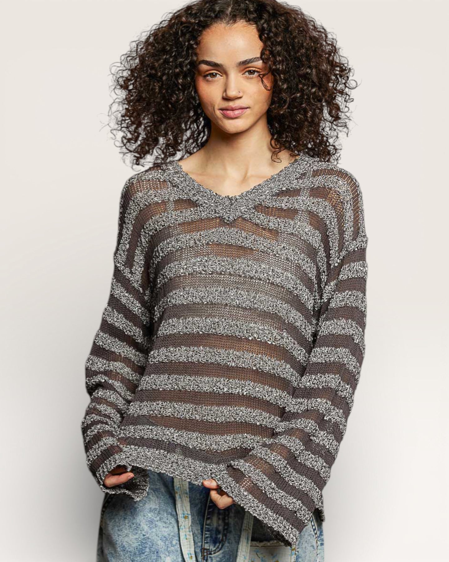 Woman wearing a gray and brown striped sweater on a plain background