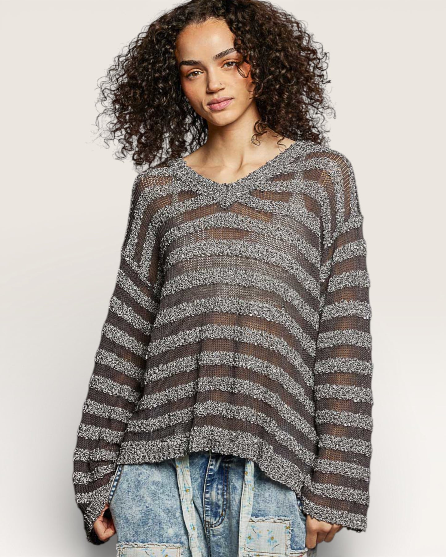 Woman wearing a striped sweater and jeans on a plain background