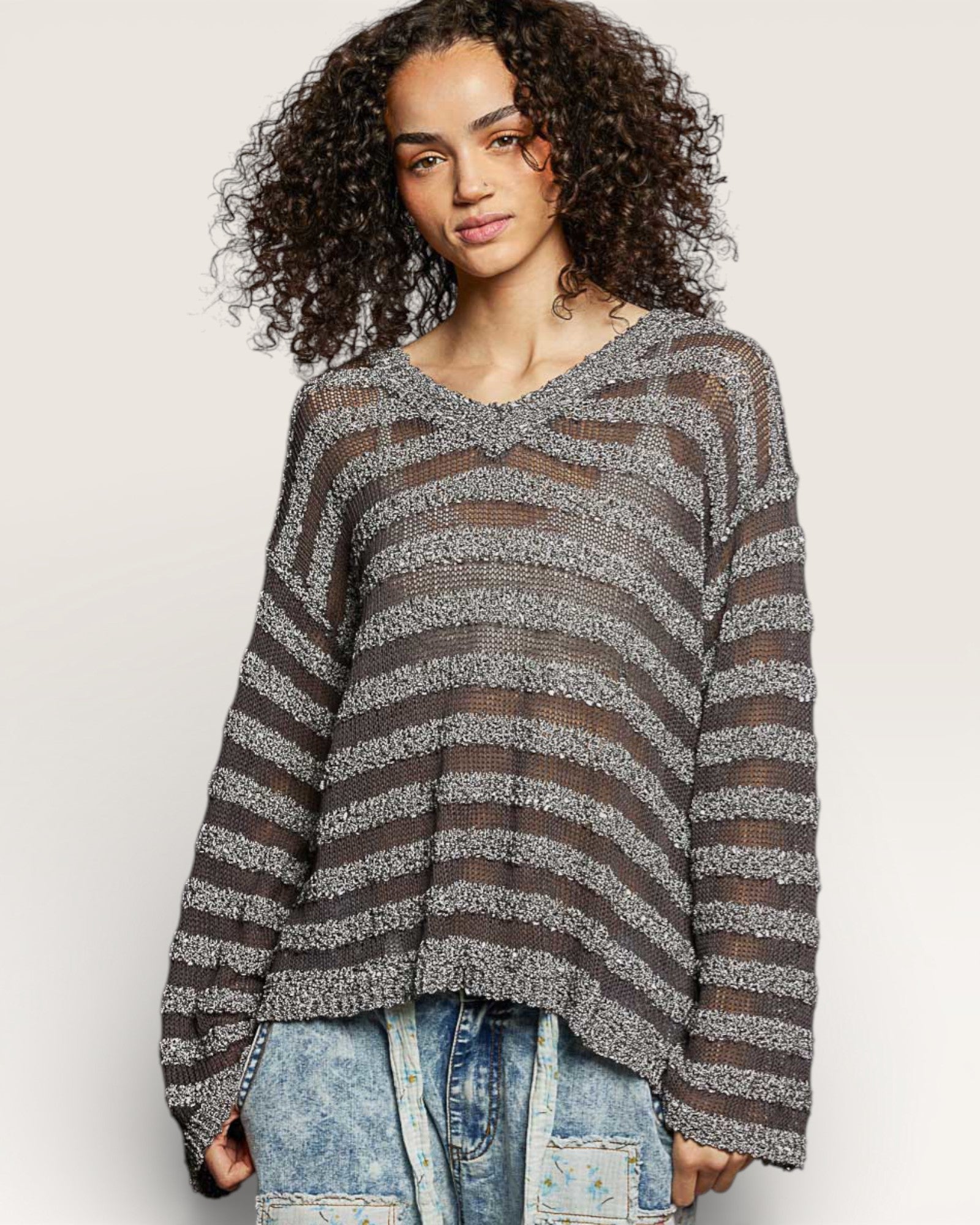 Woman wearing a striped sweater and jeans on a plain background