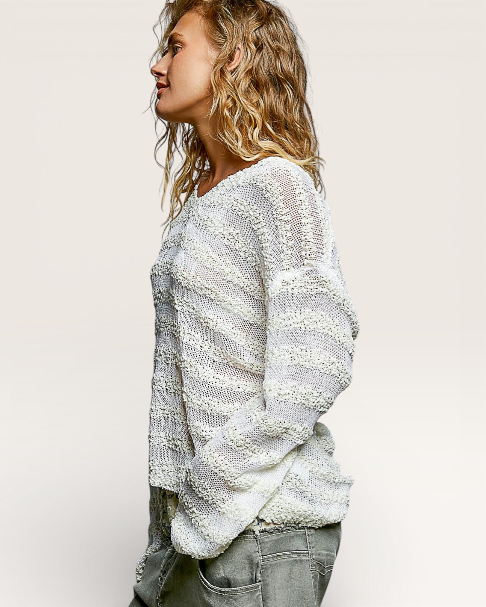 Woman wearing a textured white sweater against a plain background