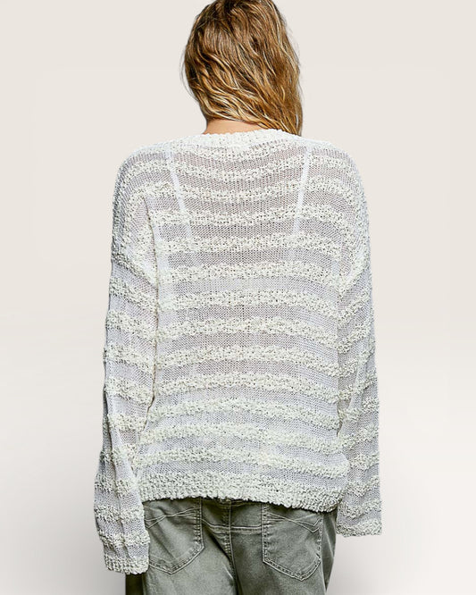 Person wearing a light gray and white striped sweater on a plain background