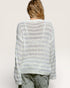 Person wearing a light gray and white striped sweater on a plain background