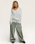 Woman wearing a light gray sweater and wide-leg jeans on a white background
