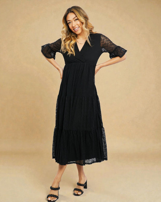 Woman wearing a black dress with lace sleeves and hem on a beige background