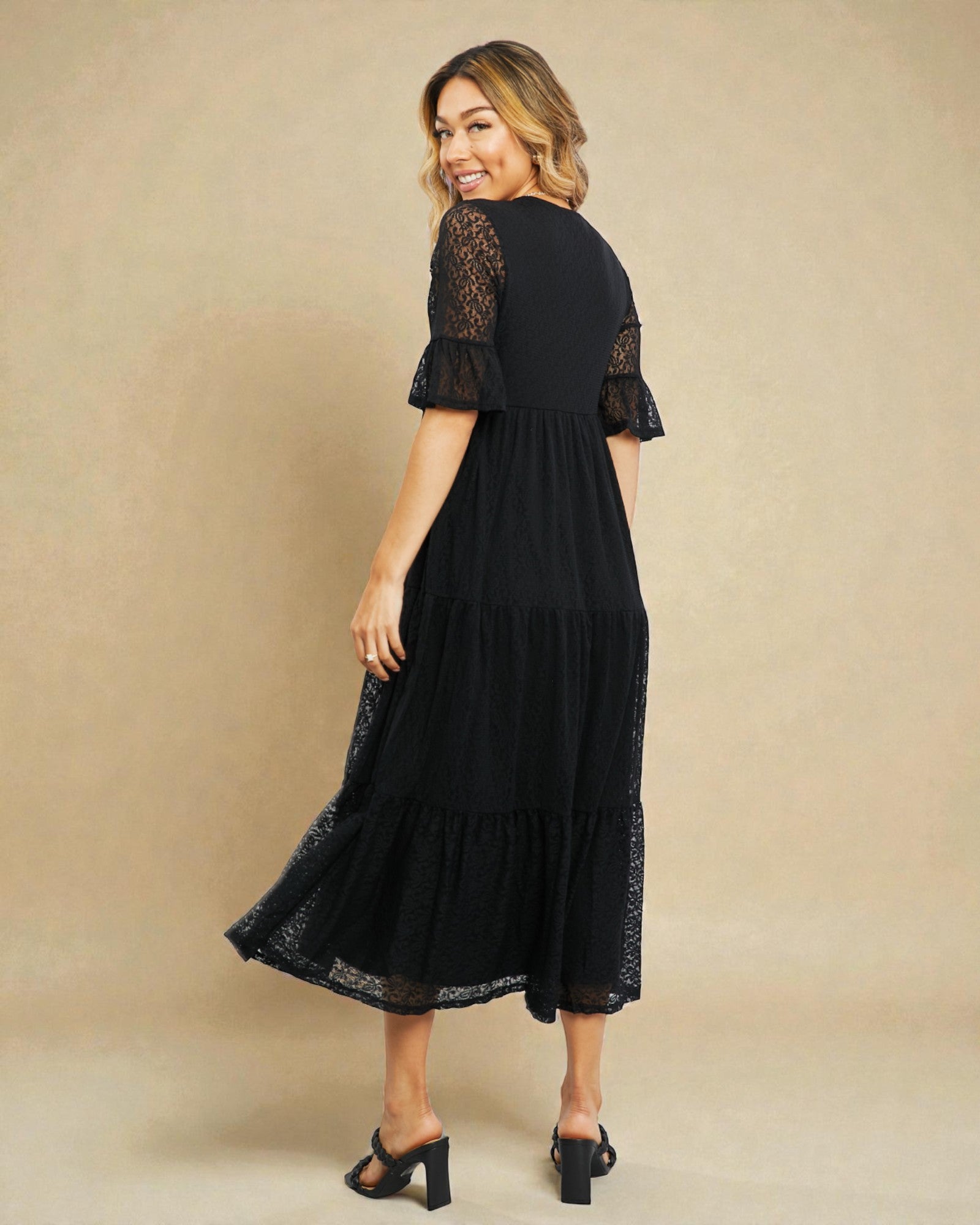 Woman wearing a black lace dress against a beige background