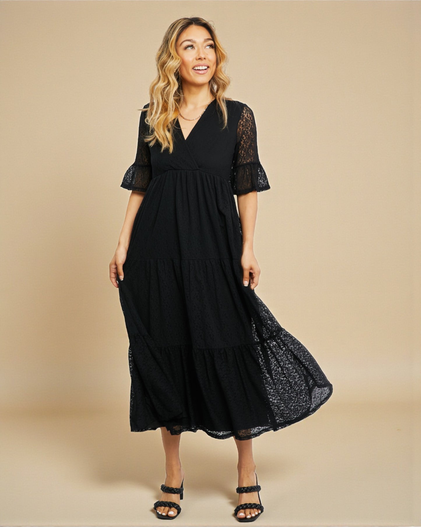 Woman wearing a black dress with lace sleeves on a beige background