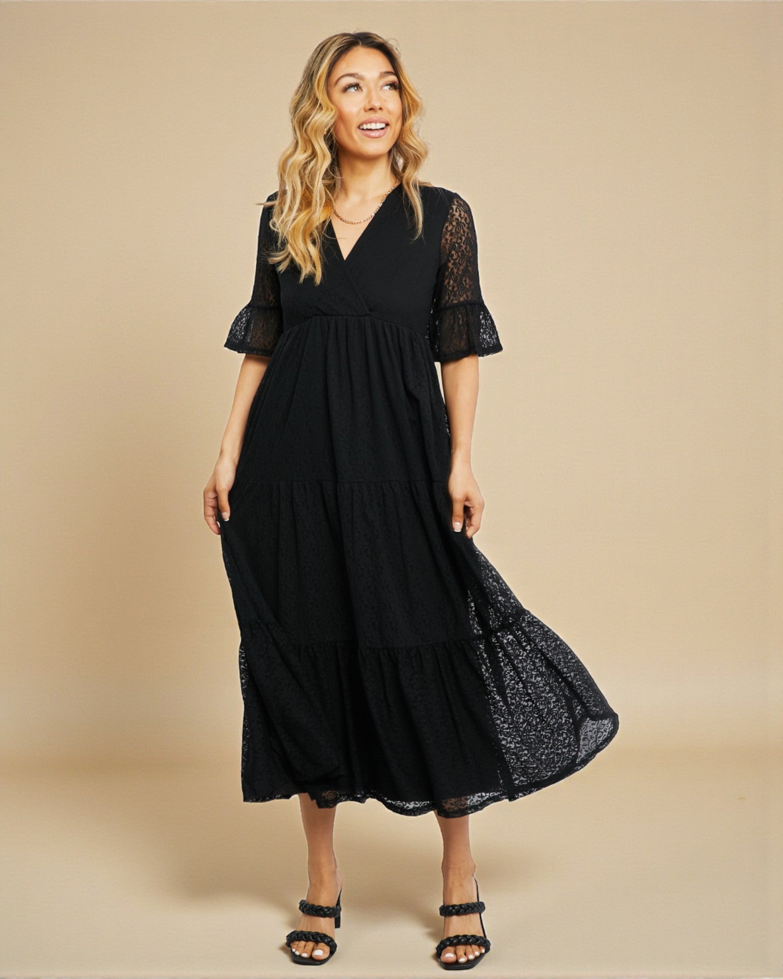 Woman wearing a black dress with lace sleeves on a beige background