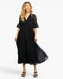 A woman modeling a black midi dress with a tiered skirt, lace short sleeves, and a V-neckline against a plain white studio background.