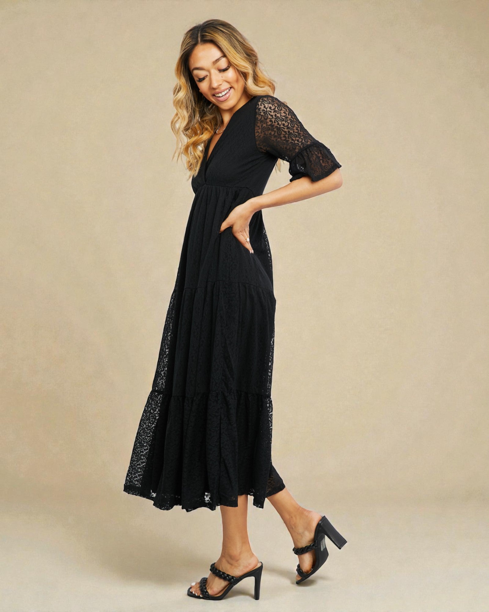 Woman wearing a black lace dress against a beige background