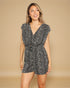 Woman wearing a black and white patterned romper on a beige background