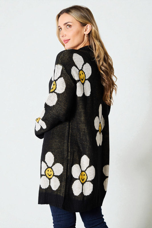 Woman wearing a black cardigan with white floral patterns on a white background