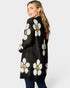 Woman wearing a black cardigan with white floral patterns on a white background