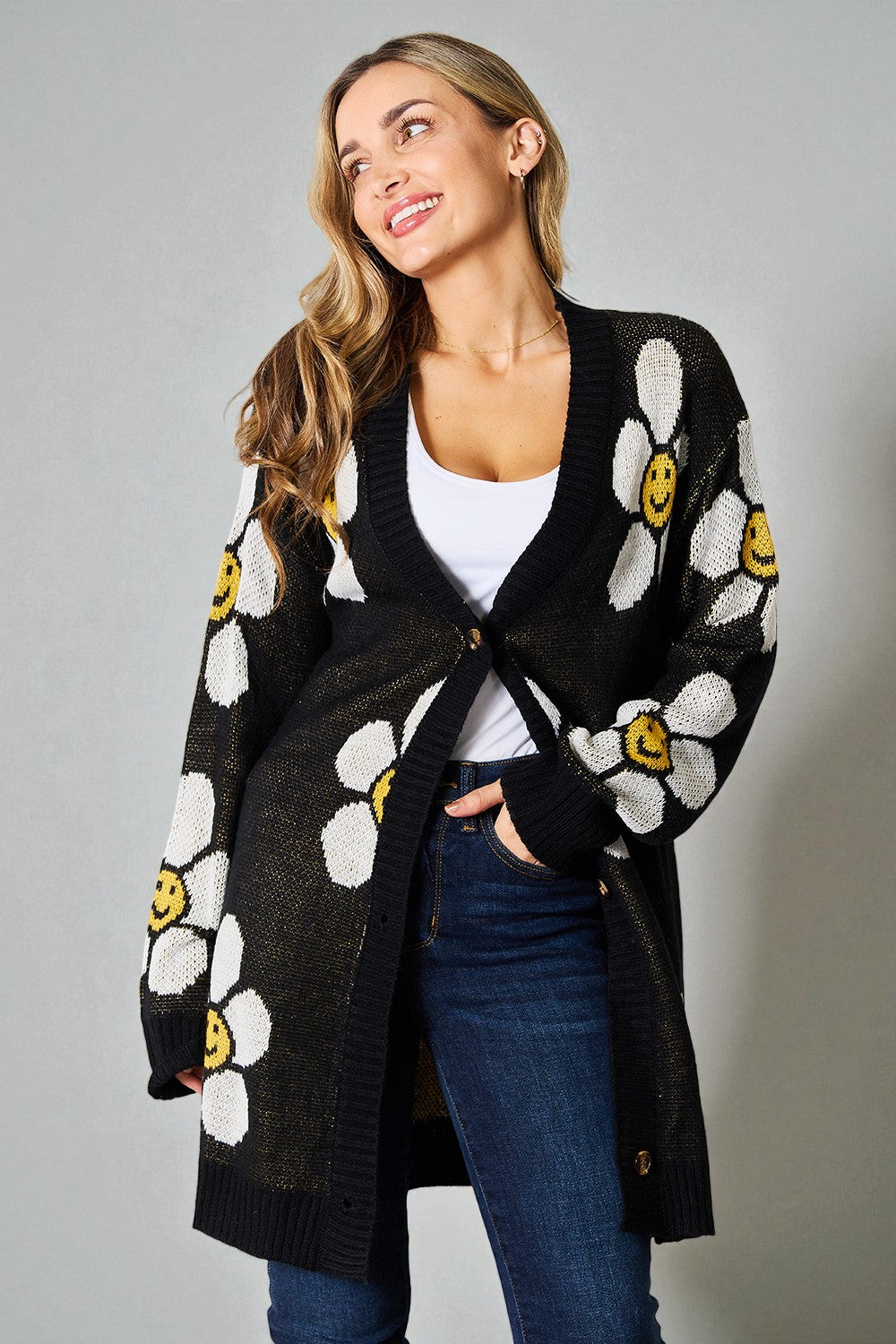 Woman wearing a black cardigan with white floral patterns on a gray background