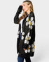 Woman wearing a black cardigan with white floral patterns on a white background