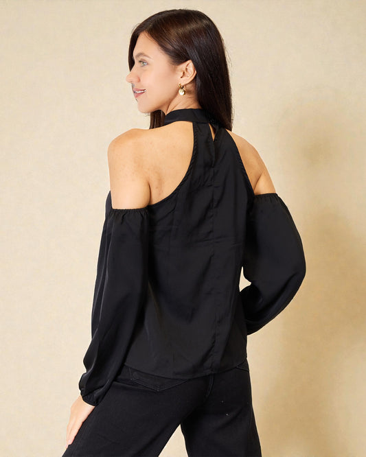 Woman wearing a black off-shoulder top and pants against a beige background